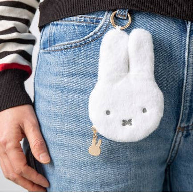 White fluffy bunny keychain attached to blue jeans