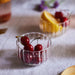 Clear glass bowls with cherries and fruit on a light fabric surface.