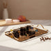 Set of four glasses with dark liquid on a gold tray, surrounded by coffee beans.