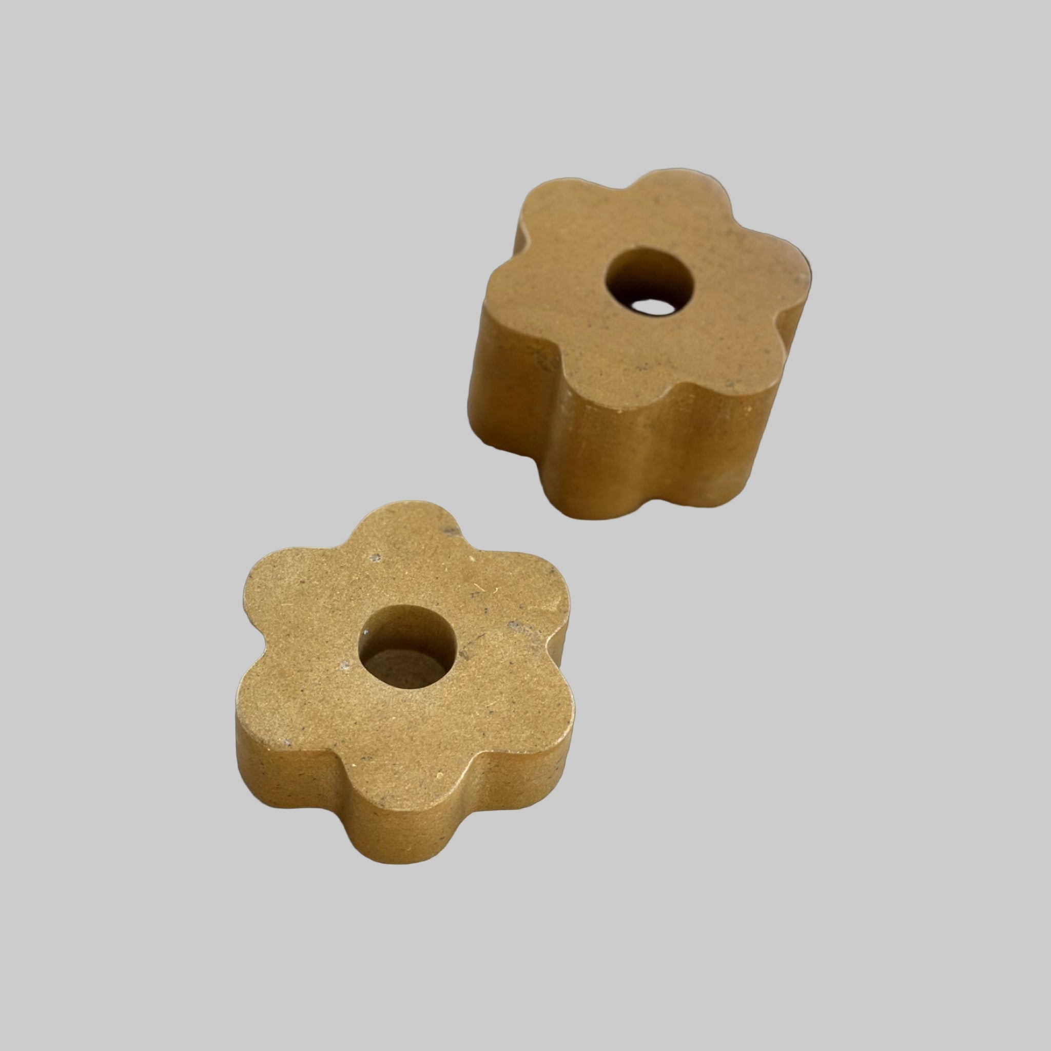 Two brown flower-shaped objects with a central hole on a light gray background