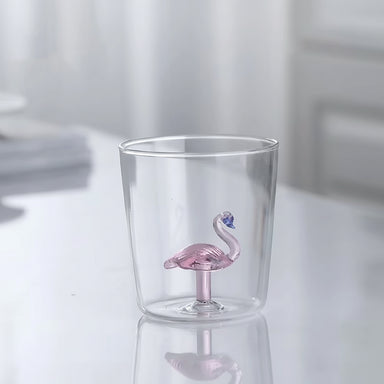 Clear glass tumbler with a pink flamingo drink valve on a white background