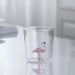 Clear glass tumbler with a pink flamingo drink valve on a white background