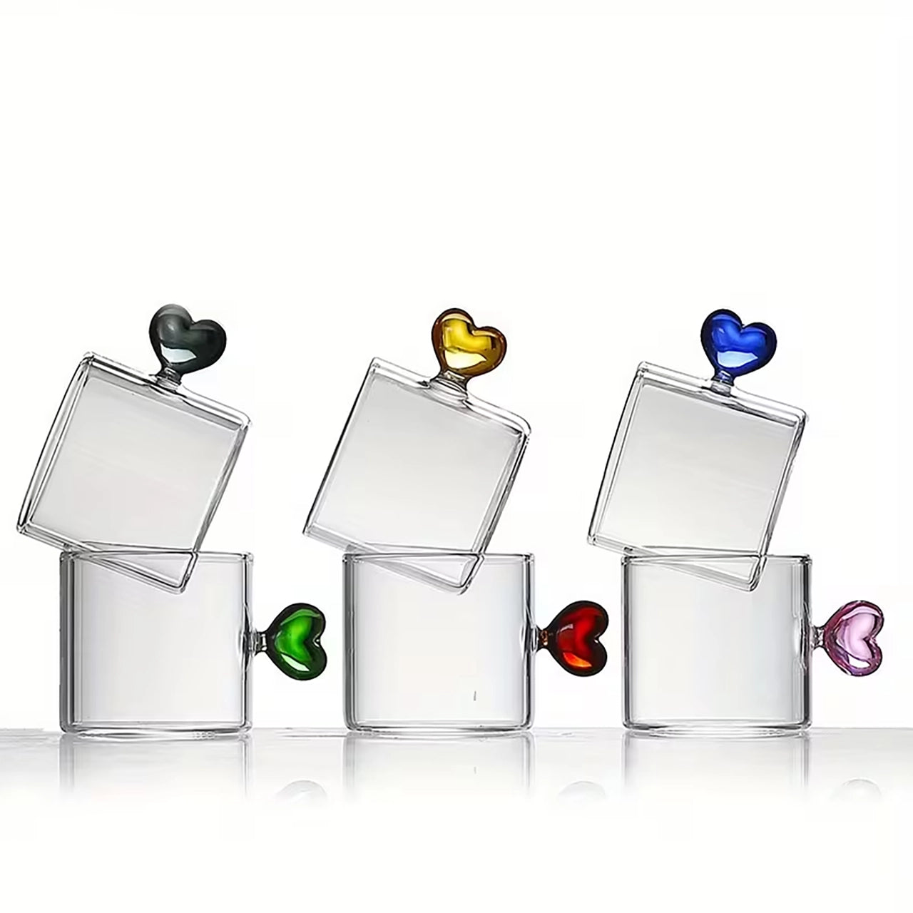Set of clear glass tumblers with colorful heart-shaped handles on a white background