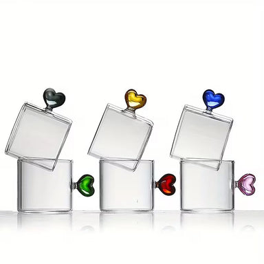 Set of clear glass tumblers with colorful heart-shaped handles on a white background